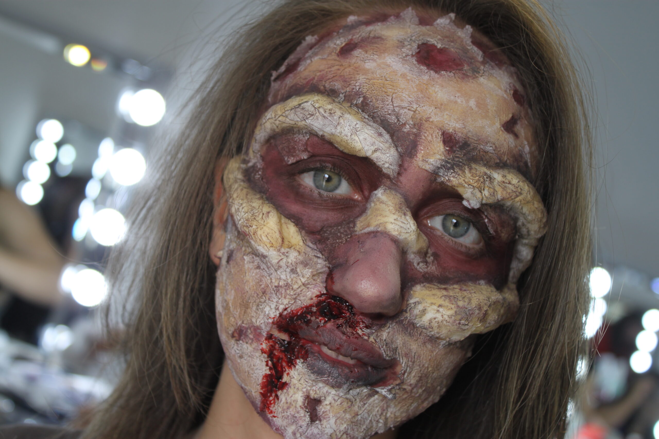 Primo piano di un trucco horror con effetti speciali sul volto e contorno degli occhi scuro.